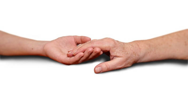 Die Hand einer Patientin wird unterstützend gehalten von einer anderen Hand.